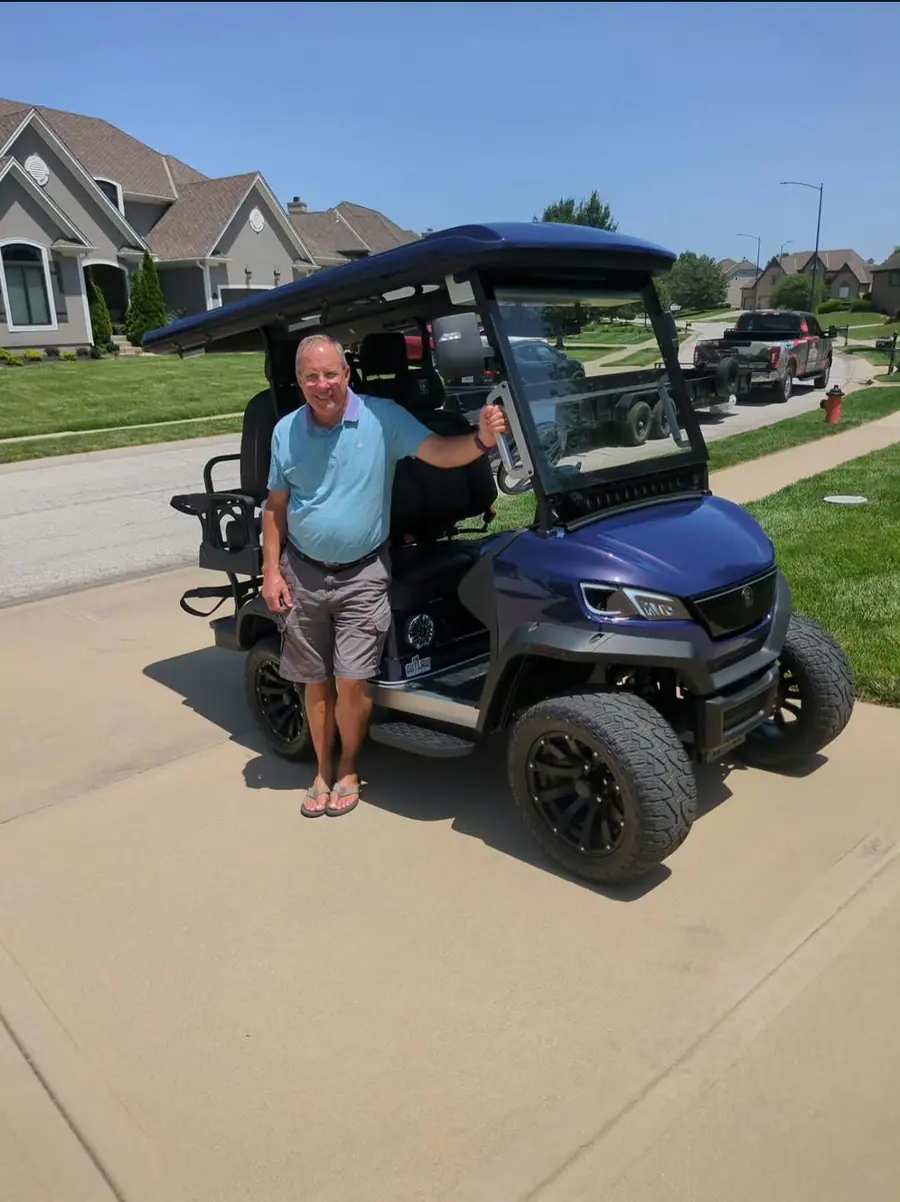 Customer standing beside his new purple lifted six-seater golf cart