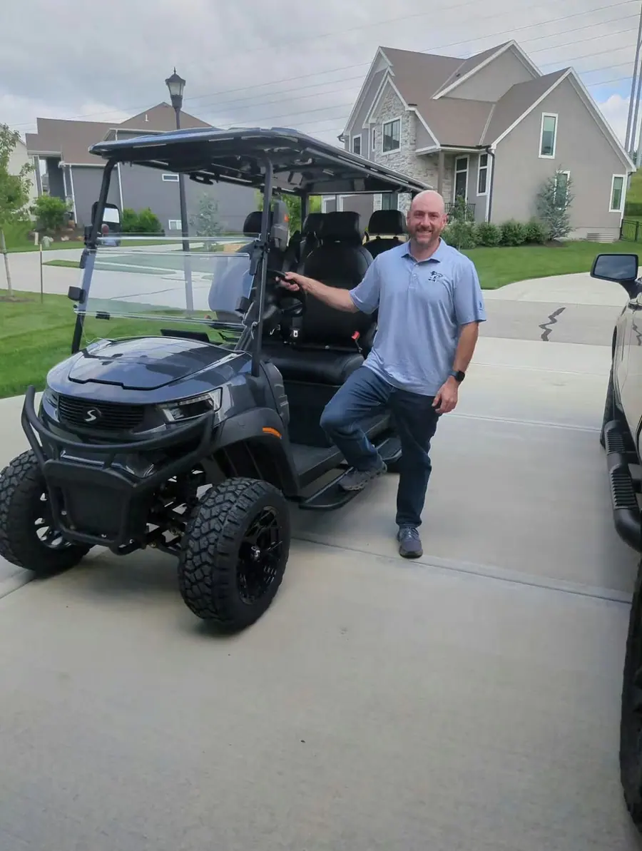 Customer standing beside his new matte black lifted golf cart